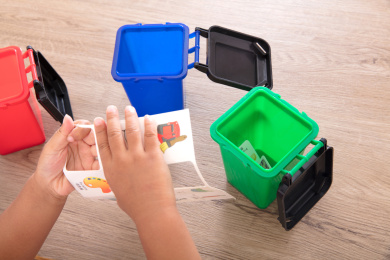 俯视拍摄小女孩正在通过小卡片和不同的垃圾桶模型学习垃圾分类小知识