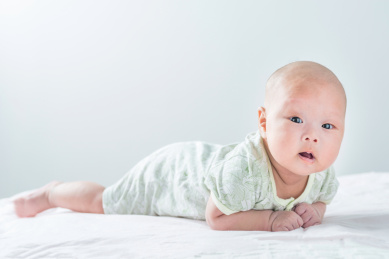 白色背景前趴着的初生婴儿