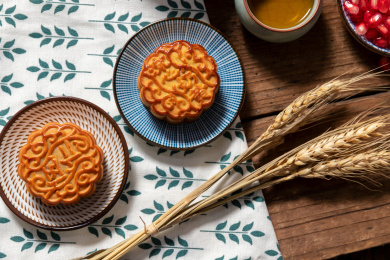 古旧木纹桌子上摆放着月饼和石榴