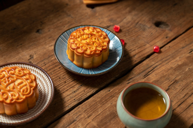 古旧木纹桌子上摆放着月饼和石榴