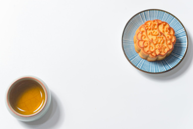 白底上对角摆放的一碟月饼和一杯茶