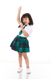 白色背景前拿着麦克风唱歌的小女孩