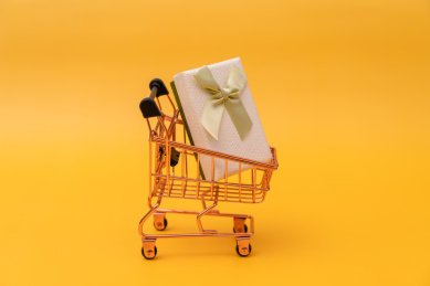 黄色背景上的购物车模型和礼品盒子