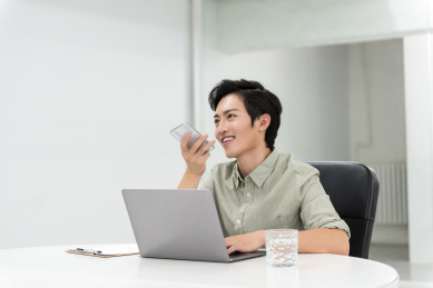 年轻的亚洲商务男性在办公室使用智能手机