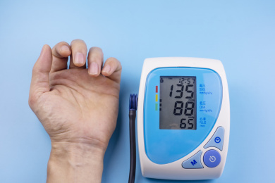 蓝色背景中有一只手和一台血压计