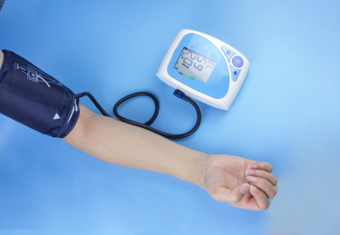 蓝色背景中的一只用胳膊正在测量血压