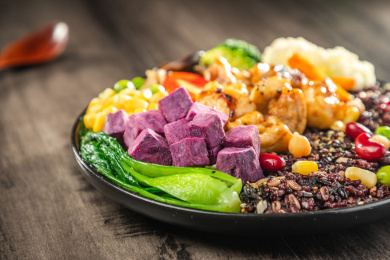  暗色木纹桌上放着一盘煎鸡腿肉黑米饭简餐