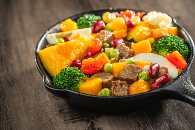 暗色木纹桌面上放着一盘煎牛肉块蔬菜沙拉