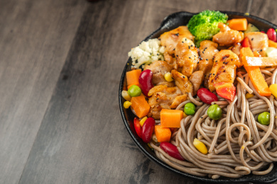 暗色木纹桌面上放着一盘煎鸡腿肉荞麦面