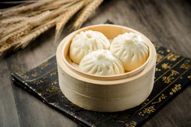 棕色木纹桌面上放着一屉蒸包子