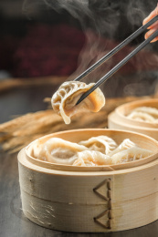 棕色木纹桌面上放着一份冒着热气的蒸饺