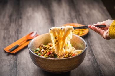 暗色木纹卓上放着一碗酸豆角炒鸡杂米粉