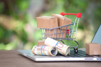 电脑键盘上的加元钞票和装满快递包裹的小购物车