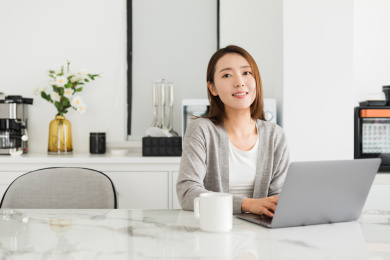 年轻女性坐在餐桌前使用笔记本电脑工作上网