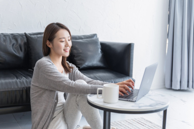 一名年轻女性坐在地毯上使用笔记本电脑休闲娱乐