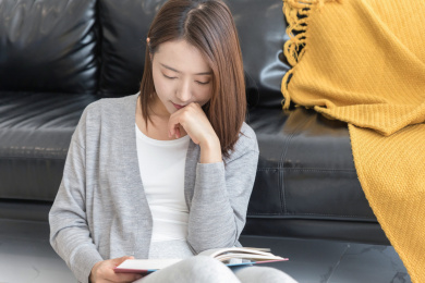 一名年轻女性坐在沙发旁边看书