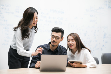 会议中一名女性指向笔记本电脑上的内容