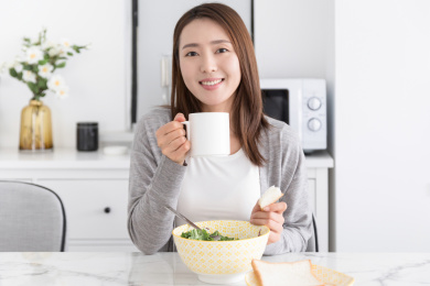 一名年轻女性在家吃早餐举起牛奶杯