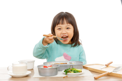 开心的拿着勺子吃饭的小女孩