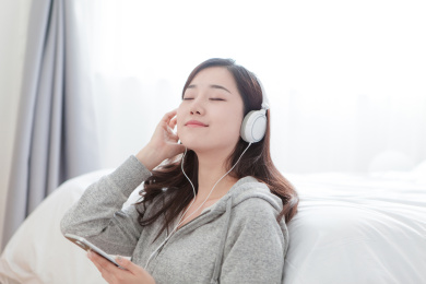 一个年轻的东方女性戴着耳机听音乐