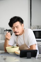 年轻亚洲男人在家吃早饭