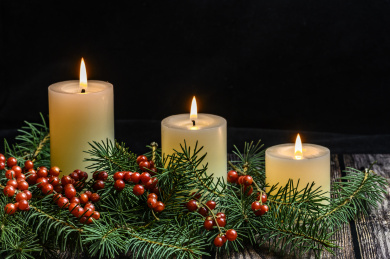 摆放在木质桌面上的圣诞树、红浆果和燃烧中的白色蜡烛