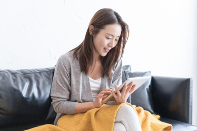 一名年轻女性坐在沙发上使用平板电脑