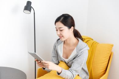 居家室内卧室使用平板电脑的女性