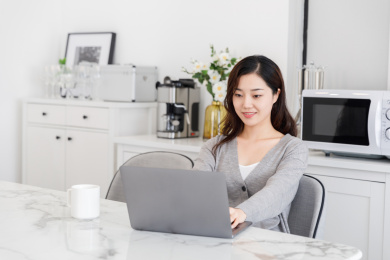 在餐厅居家办公使用笔记本电脑的女性