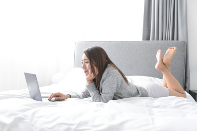 一名年轻女性在床上玩笔记本电脑