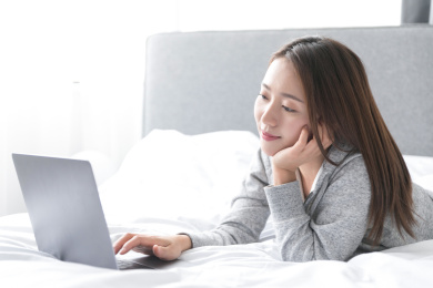 一名年轻女性在床上玩笔记本电脑