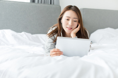 一名年轻女性在卧室看平板电脑