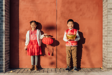 一男一女两个小孩儿在大门口拿着灯笼