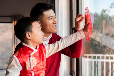 一对父子在屋内正在贴窗花