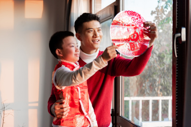 一对父子在屋内正在贴窗花