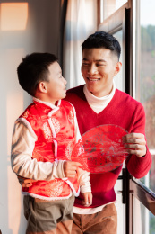 一对父子在屋内正在贴窗花