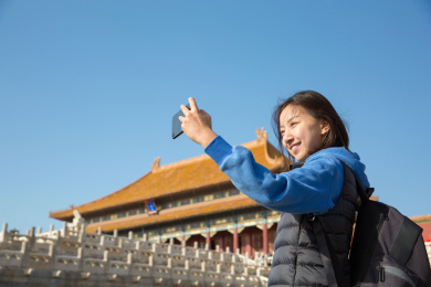 手拿智能手机在北京故宫拍照的中国女人