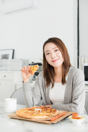 一名年轻女性在家吃外卖披萨