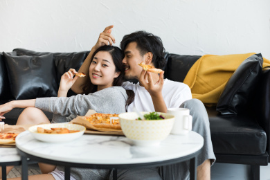 年轻情侣在客厅坐着吃披萨外卖