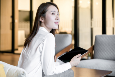 一名女性商务人士拿着平板电脑看向窗外