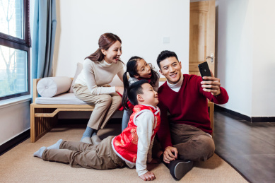 二胎家庭一家四口在除夕用手机跟家人远程通话拜年