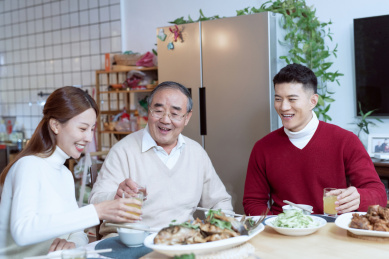 年轻夫妻在和父亲开心的一起吃饭