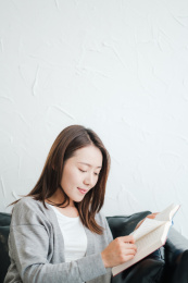 年轻漂亮女孩坐在沙发上看书