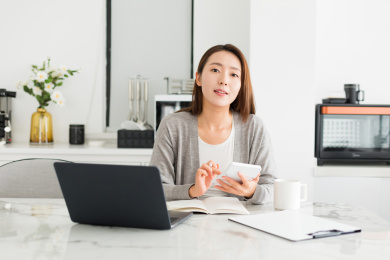 一个年轻女性坐在电脑工作看镜头