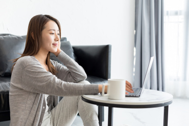 一个年轻女性在客厅使用笔记本电脑侧面