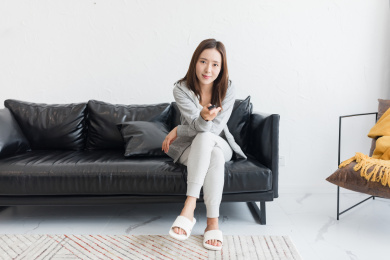 一个年轻女性坐在沙发上手拿遥控器看电视