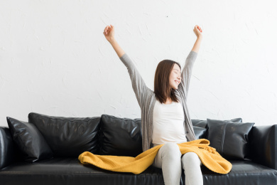 年轻女性坐在客厅沙发上拉筋伸展身体