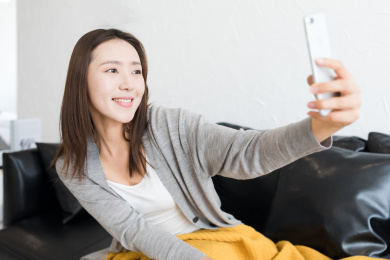 一个年轻女性坐在沙发上拿手机自拍