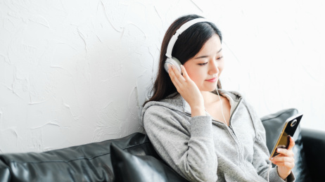 年轻女孩坐在沙发上听音乐