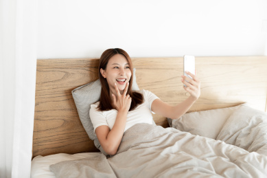 一位年轻女性在床上使用手机自拍